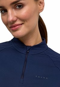 Marineblaue Quarter-Zip-Oberbekleidung mit glatter Textur, ausgestattet mit einem Teil-Reißverschluss und dezentem Branding auf der Brust. Taillierte Passform mit Nahtdetails.