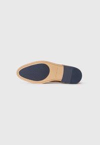 Suela de zapato con base de cuero marrón claro, tacón de goma azul y patrón de agarre texturizado. Bordes limpios y lisos con un detalle de costura mínimo.