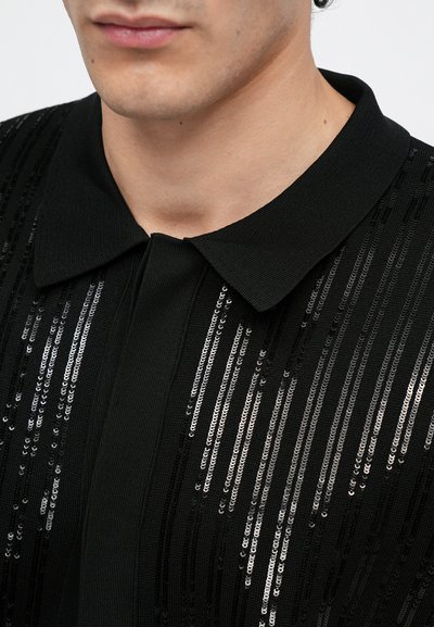 Camisa negra de manga corta con cuello estructurado, que presenta filas verticales de brillantes lentejuelas para añadir textura e interés visual.