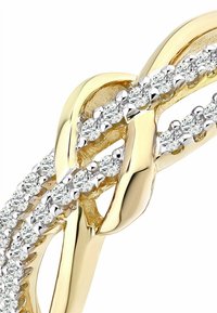 Zelta gredzens ar savītas formas dizainu un baltajiem dimantu akcentiem. Gludas, pulētas virsmas ar mirdzošu apdari. Sīki izstrādāta amatniecība ir acīmredzama.