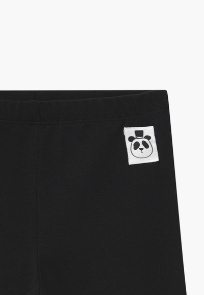 Leggings en coton noir avec un patch rectangulaire blanc portant un design de visage de panda et un haut-de-forme sur la taille. Texture lisse, tissu extensible.
