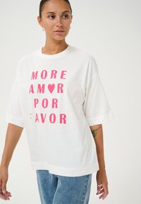 Camiseta de algodón blanca con mangas cortas. Presenta texto en negrita de color rosa: "MORE AMOR POR ♥ FAVOR." Corte clásico con cuello redondo.