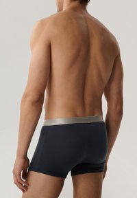 Granatowe bokserki z srebrnym pasem, o gładkiej strukturze i dopasowanym kroju, z widocznymi szwami po bokach.