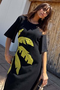 Zwarte jurk met een groot, textuur volge bladprint aan de voorkant. De jurk heeft korte mouwen en een relaxte pasvorm, met zijsplitten.