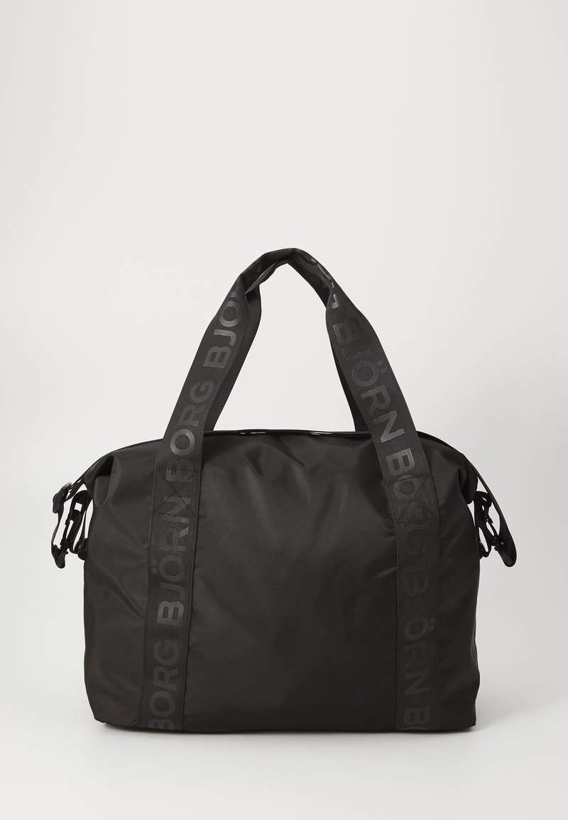 Svart duffelbag laget av teksturert stoff, med doble svarte bærestropper med preget logo og en romslig, rund kroppsdesign.