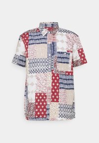Chemise à manches courtes à boutons avec un motif patchwork composé de prints géométriques et abstraits rouges, bleu marine, beige et blancs sur un fond clair.