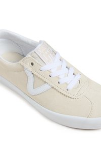 Beige suede sneaker with white lace, white rubber sole, and a white logo patch on the tongue. Features a signature side design in white.
