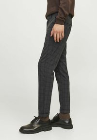 Grau karierte Hose im Slim-Fit, aus gewebtem Stoff. Verfügt über Seitentaschen und einen umgeschlagenen Saum. Kombiniert mit schwarzen Schnürschuhen.