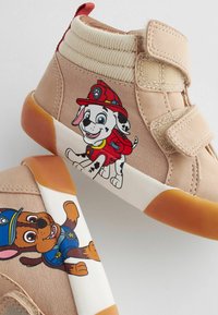 Tan Canvas-High-Top-Schuhe mit Charakterdesigns eines Feuerwehrhundes und eines Polizeihundes, mit Klettverschlüssen und Gummisohlen.