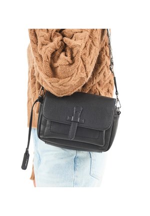 Person trägt hellblaue Jeans und einen braunen Zopfmuster-Pullover, trägt eine schwarze Leder-Umhängetasche mit einem vorderen Schnallenriemen.