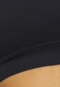 Black ribbed bra with a smooth texture. Features a soft band, stitching detail, and a seamless design for comfort and support.