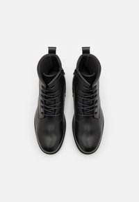 Černé kožené kotníkové boty s hladkým povrchem, vybavené šněrováním, zipem a mírně zaoblenou špičkou. Texturovaná vnitřní podšívka pro pohodlí.