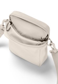 Beige Stoff-Umhängetasche mit Reißverschluss, glatter Textur, verstellbarem Riemen und einer Außentasche für einfachen Zugriff.