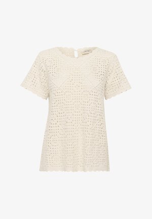 Haut en dentelle crème avec un décolleté festonné, des manches courtes et des découpes en forme de diamant tout au long du tissu. Détail en forme de trou clé à l'arrière.