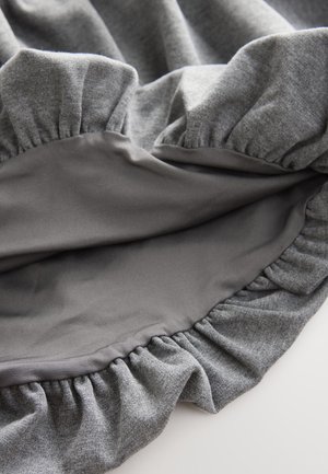 Textile gris avec un bord froncé, présentant une doublure intérieure lisse et une texture contrastée, alliant un matériau doux et extensible.
