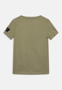 Maglietta a maniche corte verde oliva realizzata in cotone. Presenta un collo rotondo e un'etichetta nera sulla manica sinistra. Tessuto semplice e liscio.