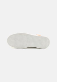 White rubber shoe sole with a textured grid pattern, featuring a small orange accent on the side. Smooth finish throughout.