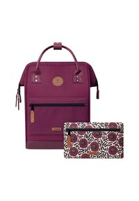 Lila Stoff-Rucksack mit glatter Textur, ausgestattet mit zwei oberen Griffen, einer vorderen Reißverschlusstasche und einem abnehmbaren, gemusterten Täschchen mit floralem Design.