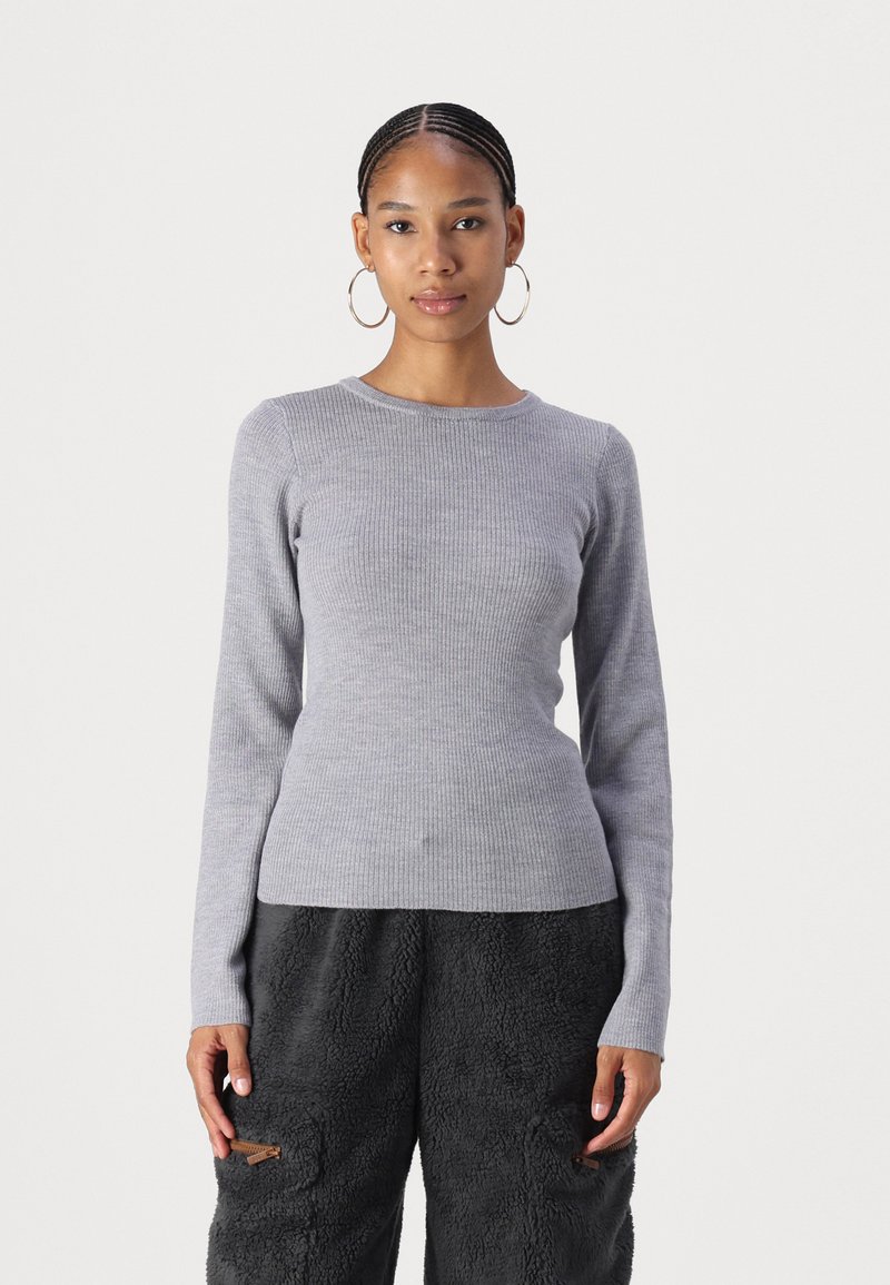 Pull gris à manches longues en rib avec col rond, silhouette ajustée et texture douce, associé à un pantalon noir en peluche avec poches.