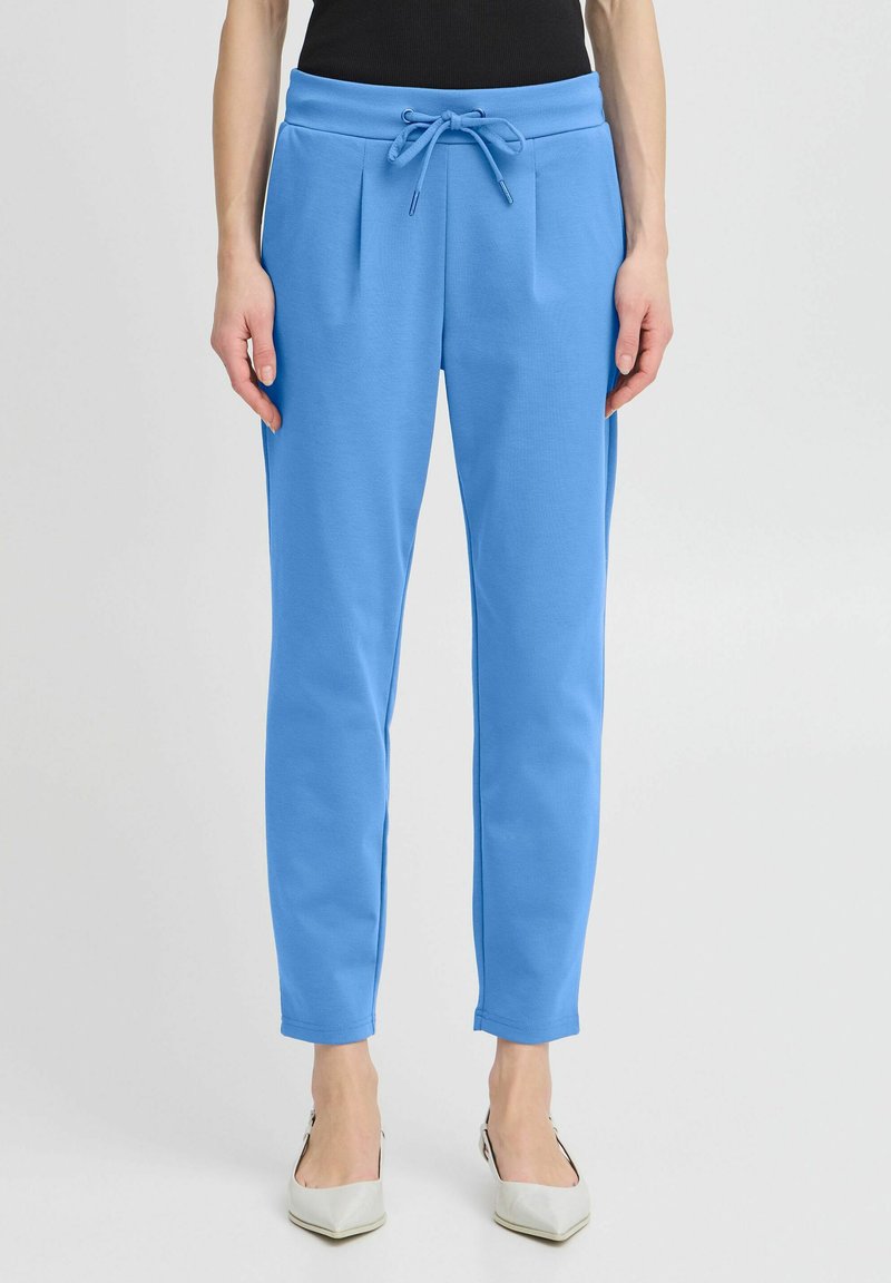 Light blue sweatpants with a drawstring waist, pleated front design, tapered legs, and soft fabric texture.