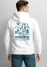 Weißer Kapuzenpullover mit einer Yosemite-California-Grafik in Türkis, die Berge, Bäume und einen Fluss zeigt. Hergestellt aus weichem Stoff.