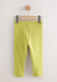 Grüne Kinderleggings aus weichem, elastischem Stoff mit glatter Oberfläche und knöchellangem Schnitt. Auf einem Holzkleiderbügel aufgehängt.