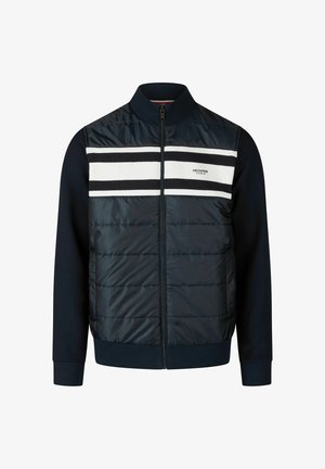 Marineblauwe jas met een gewatteerde bovenkant, witte en zwarte horizontale strepen, ritssluiting aan de voorkant en ribgebreide manchetten. Gemaakt van gemengde materialen voor warmte.