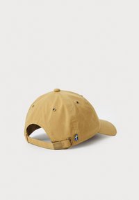 Khaki baseballkeps med böjd skärm, texturerad tyg, metallspänne för justering och en liten blå och gul flagg-symbol på baksidan.