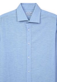 Camicia azzurra chiara a maniche corte, realizzata in un tessuto testurizzato. Presenta un colletto classico e una fila di bottoni bianchi lungo il davanti.