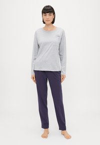 Sivá košeľa s dlhým rukávom a vreckom, zdobená �čiernou kvetinovou výšivkou, skombinovaná s fialovými, voľnými nohavicami. Hladká textúra, ležérny strih.