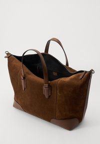 Brun ruskinds tote bag med læderdetaljer, lynlåslukning og dobbelte håndtag. Har et rummeligt indre med sort foder.