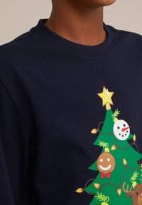 Mornarska majica z dolgimi rokavi z barvnim motivom božičnega drevesca z okraski, zvezdo in lučmi, natisnjena na mehkem bombažnem materialu.
