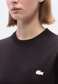 Η μαύρη φούτερ μπλούζα διαθέτει στρογγυλή λαιμόκοψη, ριμπ μανσέτες και κεντημένο λευκό λογότυπο στο αριστερό στήθος. Ομαλή υφή, άνετη εφαρμογή.