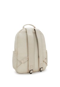 Mochila beige hecha de tela ligera, con correas de hombro acolchadas, textura suave, bolsillo lateral y un diseño de parte superior redondeada.