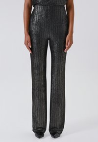 Pantaloni neri a gamba larga realizzati in un tessuto lucido e testurizzato con righe verticali. Presentano una vita alta e una silhouette svasata.