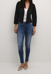 Svart kort blazer med trekvartslånga ärmar, tillsatt med ljusblå skinny jeans och beige spetsiga klackar. Vit linne under.