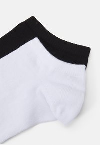 Witte katoenen sok met een zwarte boord. De stof is glad met een ribbelstructuur langs de boord, ontworpen voor comfort en een goede pasvorm.
