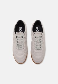 Lys grå semsket skinn sneakers med teksturdetaljer, rund tå og gummisåle. Har grå snøringer og en svart innersåle med logo.