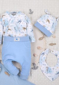 Baby-outfitset met oceaanthema prints, inclusief octopus, zeepaardje en vis; lichtblauwe broek, hoed met knopen en bijpassend slabbetje op een gestructureerde achtergrond.