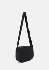 Črn pravokotni crossbody nahrbtnik z zadrgo, ki ima usklajen vzorec in nastavljiv trak. Gladek material z rahlim sijajem.