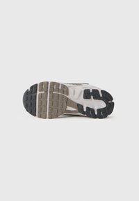 Laufschuhe mit einer strukturierten Gummisohle, die schwarze, graue und beige Abschnitte aufweist. Das Design beinhaltet Rillen und Kerben für besseren Halt.