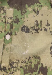Kamouflagem�önstrad tyg med gröna, oliv och svarta nyanser. Inkluderar en tryckknappdetalj på vänster sida, med en slät yta.