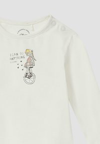 Witte langjarige top met een bedrukte afbeelding van een meisje op een eenwieler, met de tekst "IK KAN ALLES DOEN" en decoratieve hartjes.