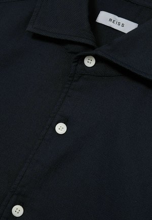 Cămașă texturată de culoare bleu marin, cu guler tip button-down și nasturi albi, având o etichetă REISS pe gulerul interior.