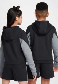 Svarta huvtröjor med grå ärmar, med ribbat fåll och muddar. Bärs med matchande svarta shorts, vilket visar en sportig design.