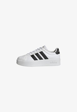 Witte sneaker met drie zwarte strepen aan de zijkant, bovenwerk van getextureerd leer, ronde neus en dikke witte zool. Gebrandmerkt met het "adidas" logo.