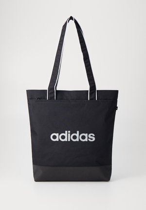 Melnā boksa soma ar pelēko "adidas" logotipu, izgatavota no izturīga auduma, ar divām plecu siksnām un kontrastējošu melnu apakšpaneli.