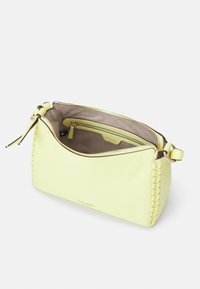 Bolso de cuero amarillo con detalles tejidos, cierre de cremallera y una sola correa para el hombro. El interior cuenta con un bolsillo con cremallera y forro beige.