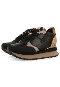 Chaussures de sport noires et grises avec une tige texturée, des accents en daim et une semelle épaisse beige. Présente un talon métallique argenté.