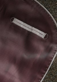 Burgundy fabric with a herringbone pattern, featuring a gray satin strap and a circular hardware accent. Smooth texture, finished edges.
